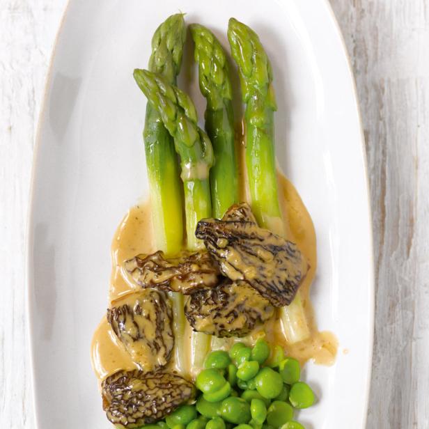 Spargel mit Morcheln und grünen Bohnen auf einem weißen Teller.