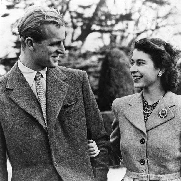 Ein Schwarzweißfoto von Prinz Philip und Königin Elisabeth II., die sich anlächeln.