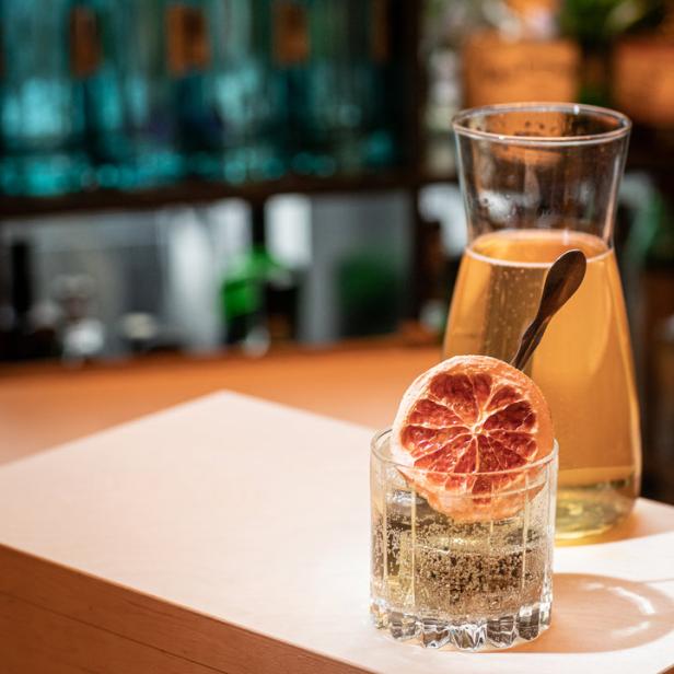 Ein Cocktail mit einer Orangenscheibe als Dekoration steht auf einer Bar.