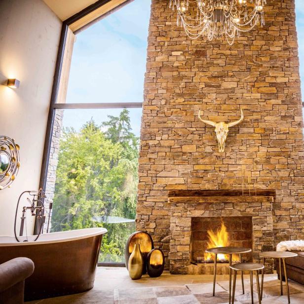 Ein luxuriöses Wohnzimmer mit Kamin, Geweih und Blick auf den Wald.