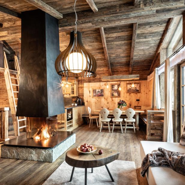 Ein gemütliches Wohnzimmer mit Holzwänden, einem Kamin und einem Esstisch.