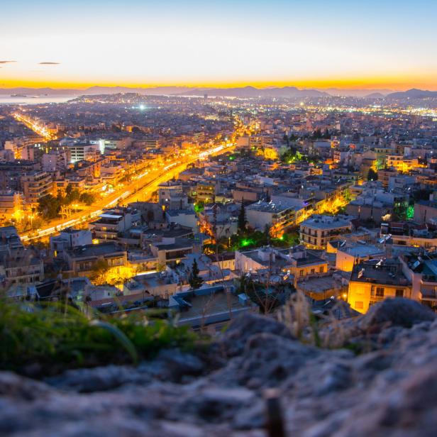 Blick auf Athen bei Dämmerung mit beleuchteten Straßen.