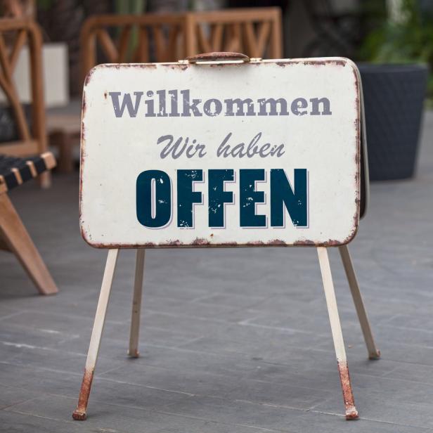 Ein Schild verkündet: „Willkommen. Wir haben OFFEN.“