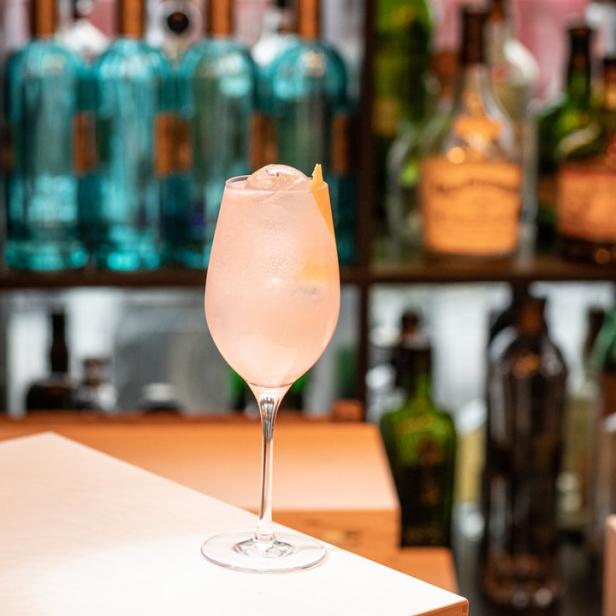 Ein „Rubin Spritz“ Cocktail steht auf einer Bar.