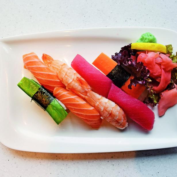 Eine Platte mit verschiedenen Sushi-Sorten, darunter Lachs, Garnele und Thunfisch.