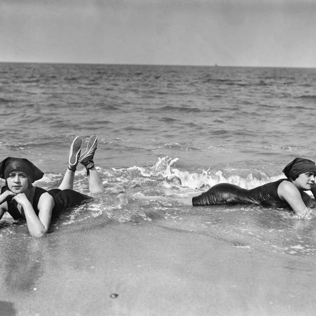 Zwei Frauen liegen im Wasser an einem Strand.