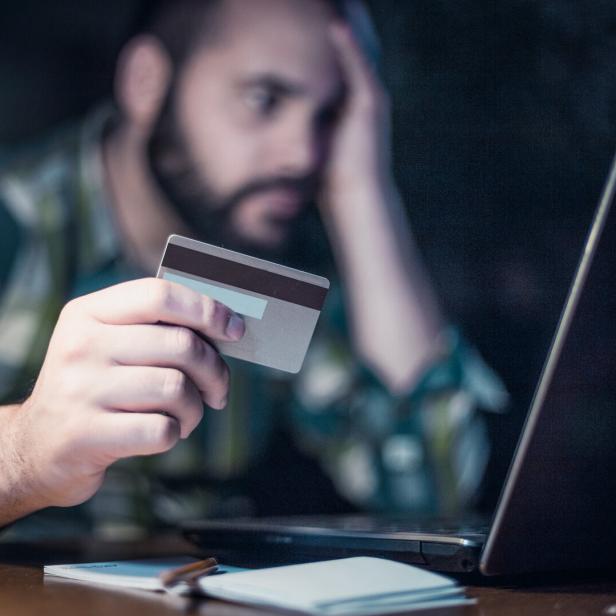 Close-up of a man paying bills from home by using a laptop and a credit card