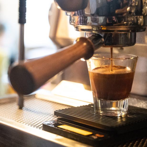 Eine Espressomaschine füllt ein kleines Glas mit frisch gebrühtem Kaffee.