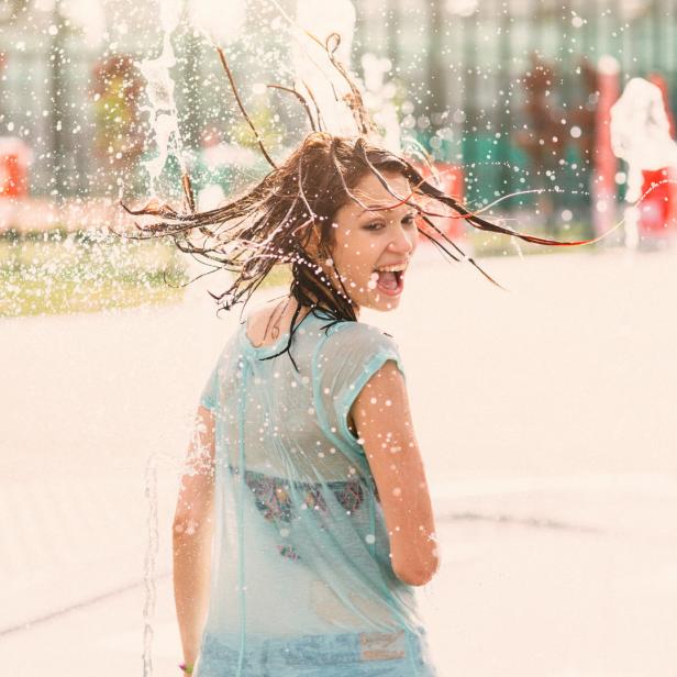 Eine junge Frau hat Spaß in einem Wasserspielplatz.