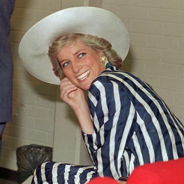Prinzessin Diana lächelt in einem gestreiften Blazer und einem Hut.