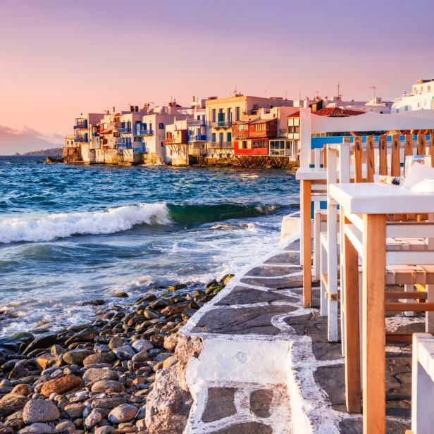 Blick auf das malerische Klein-Venedig in Mykonos mit Tischen im Vordergrund.