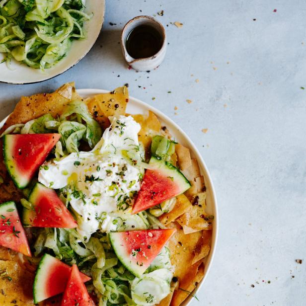 Ein Teller mit Wassermelonenstücken, Burrata und knusprigen Teigstücken.
