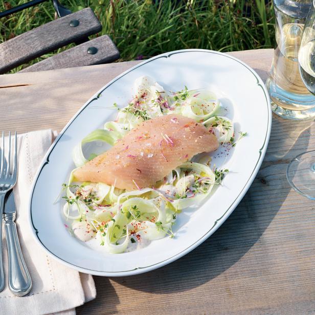 Ein Teller mit Fisch auf Gurkensalat, serviert im Freien.
