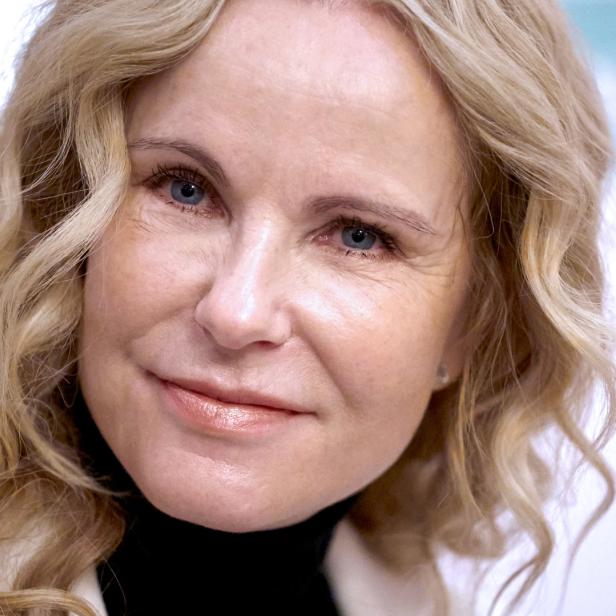 Porträt einer lächelnden Frau mit blonden, gewellten Haaren.