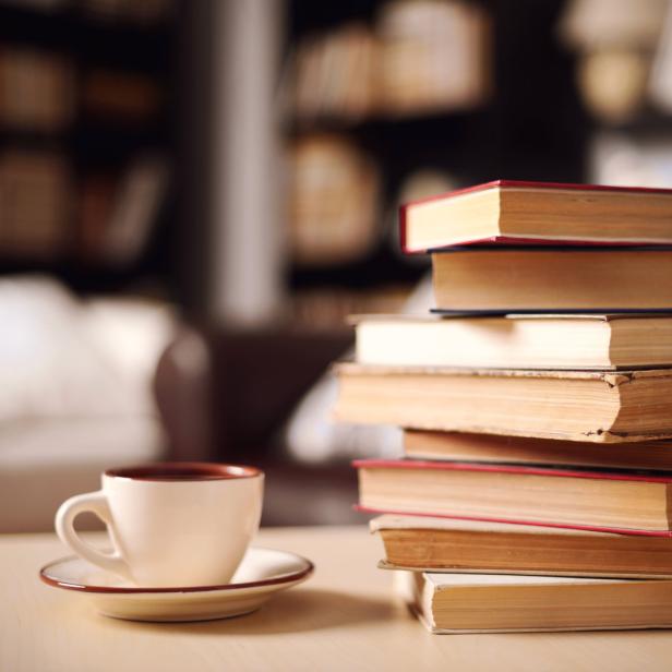 Eine Tasse Kaffee steht neben einem Stapel alter Bücher.