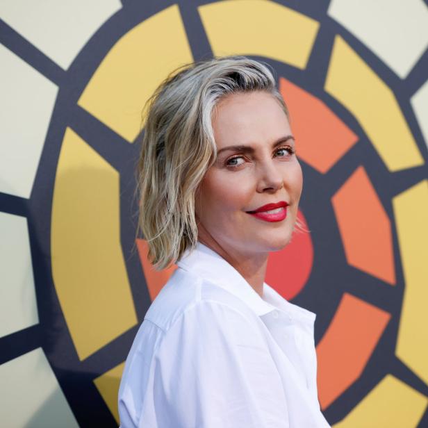 Charlize Theron posiert vor einem farbenfrohen Hintergrund.
