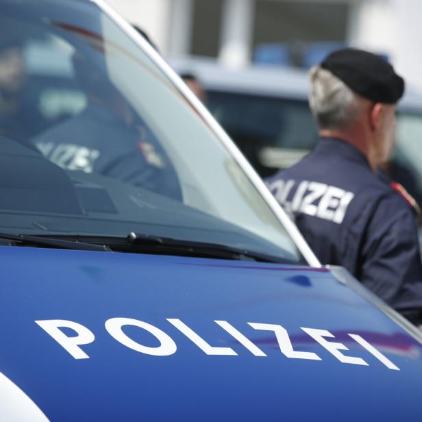 Eine Polizistin steht neben einem Polizeiauto.