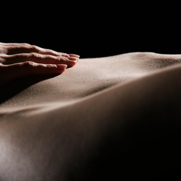 Eine Hand liegt auf dem Bauch einer Frau.