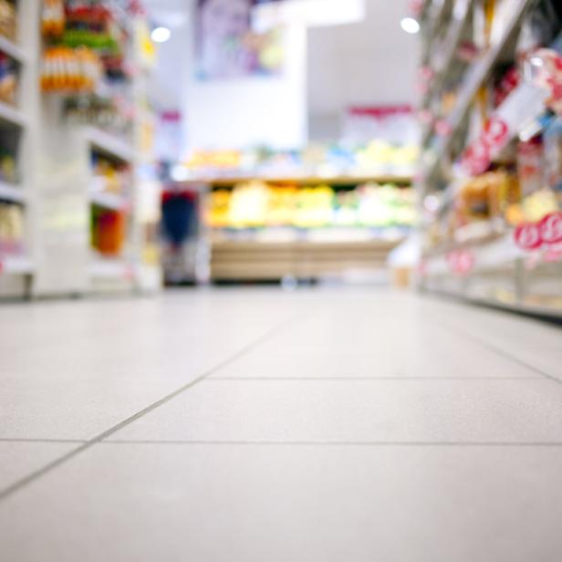 Ein Blick auf den gefliesten Boden eines Supermarktes mit Regalen im Hintergrund.