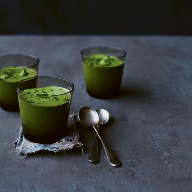 Drei Gläser mit grünem Matcha-Dessert und zwei Löffel auf einem Tisch.