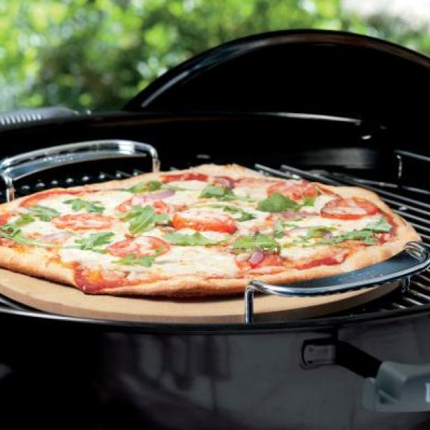 Eine Pizza mit Tomaten und Basilikum wird auf einem Grill zubereitet.