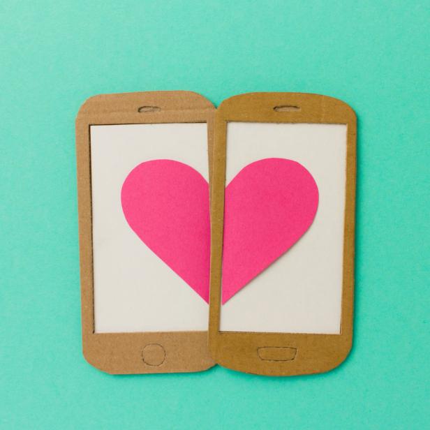 Zwei Papp-Smartphones bilden zusammen ein rosa Herz.