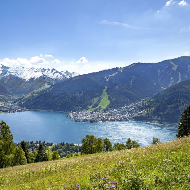 Blick auf Zell am See mit dem Zeller See und schneebedeckten Bergen im Hintergrund.