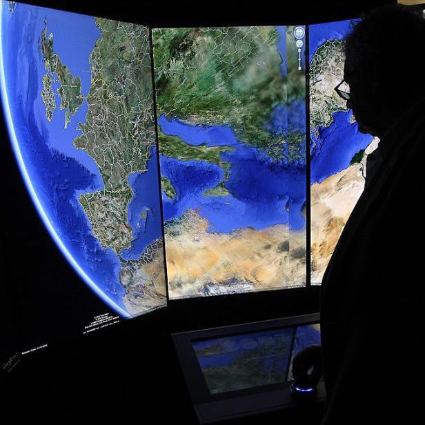 Eine Person betrachtet eine große Anzeige von Google Earth, die Europa und Afrika zeigt.