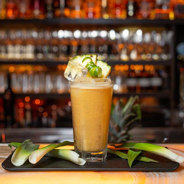 Ein Cocktail mit Ananas und Eiswürfeln auf einer Bar.