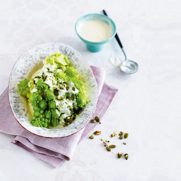 Ein Teller mit Romanesco-Brokkoli, garniert mit einer hellen Soße und Kürbiskernen.