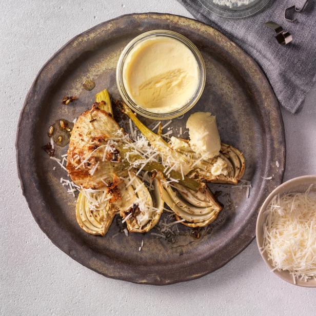 Gegrillter Fenchel mit Parmesan und einer cremigen Sauce auf einem Teller angerichtet.
