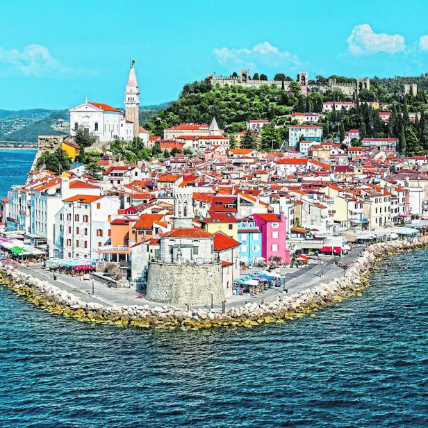 Luftaufnahme der Küstenstadt Piran in Slowenien mit der Kirche St. Georg und der Burg auf dem Hügel.