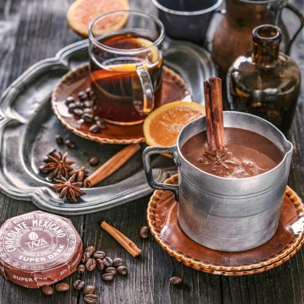 Ein Tisch mit heißer Schokolade, Kaffee, Orangenscheiben und Gewürzen.