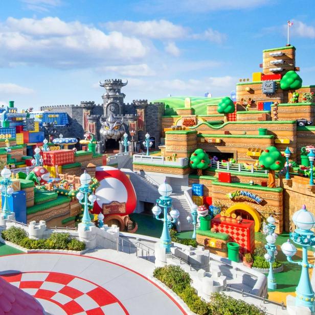 Blick auf die farbenfrohe Themenwelt „Super Nintendo World“ mit Peachs Schloss und Bowsers Festung.