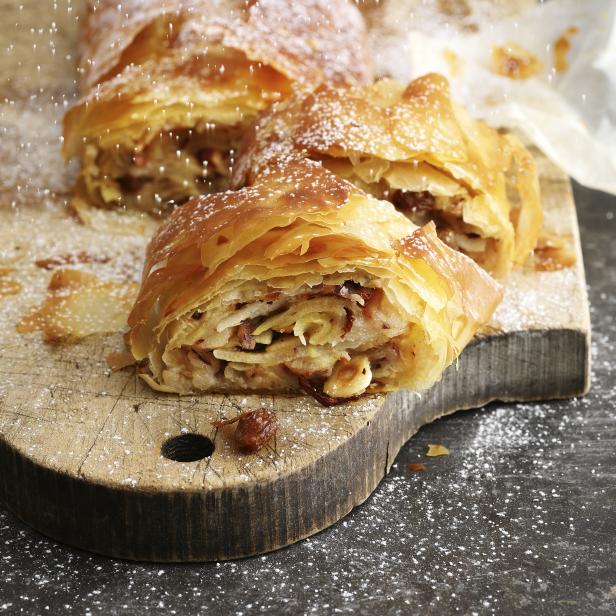 Ein aufgeschnittener Apfelstrudel wird mit Puderzucker bestreut.