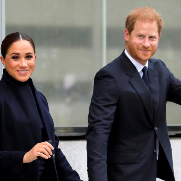 Meghan Markle und Prinz Harry lächeln und winken in die Kamera.