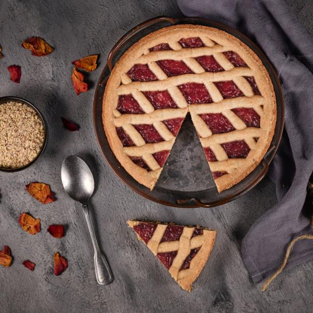 Eine Linzer Torte mit einem herausgenommenen Stück auf einem Teller.