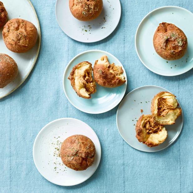 Mehrere gefüllte Brötchen liegen auf Tellern auf einem blauen Tuch.