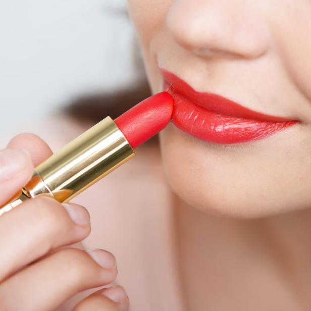 Eine Frau trägt roten Lippenstift auf.