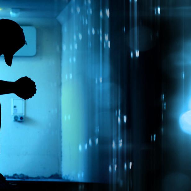 Ein junger anonymer Mann sitzt mit hängenden Schultern auf einer Bank.