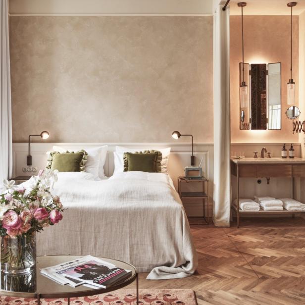 Ein Hotelzimmer mit einem Doppelbett, einem Blumenstrauß und einem angrenzenden Badezimmer.