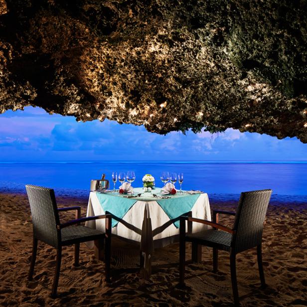 Ein romantisches Abendessen in einer Höhle am Strand mit Blick auf das Meer.