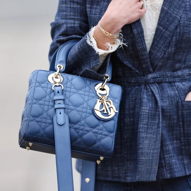 Nahaufnahme einer blauen „Lady Dior“-Handtasche, getragen mit einem passenden Blazer.