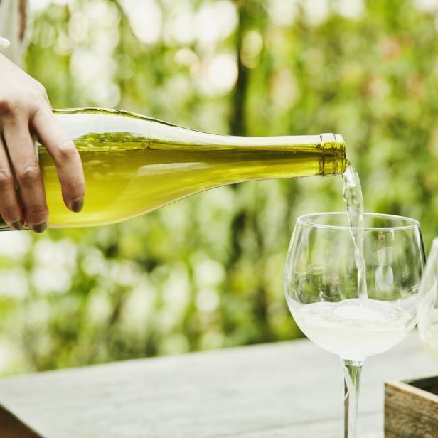 Eine Person schenkt Weißwein in ein Glas ein.