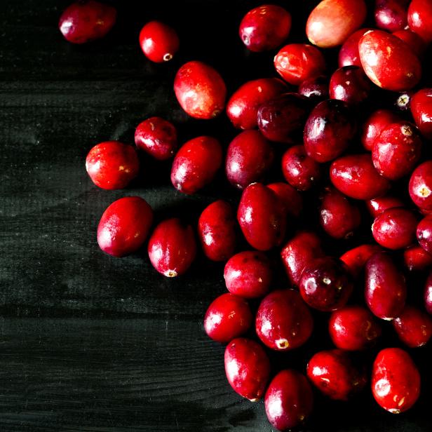 Eine Ansammlung von roten Cranberries auf einer dunklen Holzoberfläche.