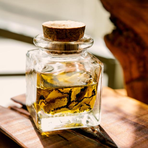 Eine Glasflasche mit Trüffelöl steht auf einem Holzbrett.