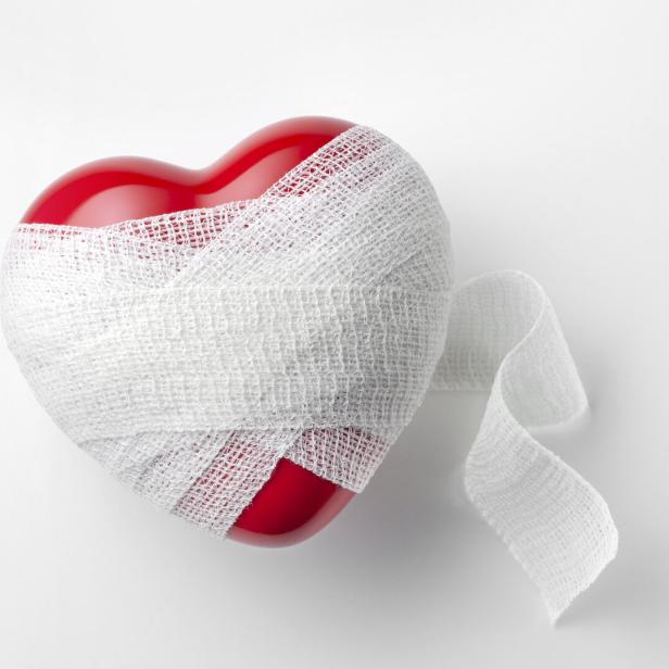 Ein rotes Plastikherz in einer Bandage.