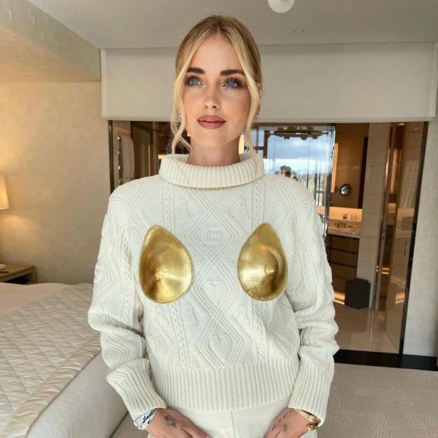 Chiara Ferragni posiert in einem weißen Pullover mit goldenen Applikationen.
