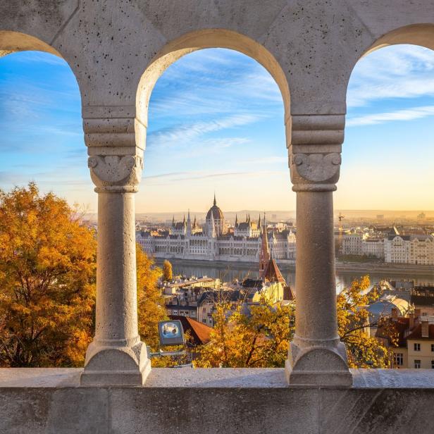 Blick durch drei Steinbögen auf das ungarische Parlament in Budapest.
