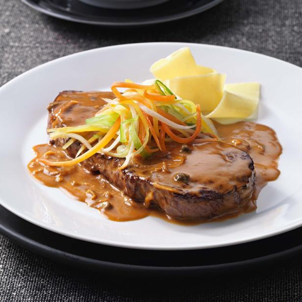 Ein Teller mit Rinderfilet in Sauce, garniert mit Gemüsejulienne und Bandnudeln.